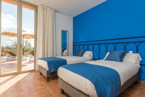 two beds in a bedroom with blue walls and a patio at Son Bordils in Inca