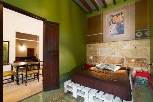um quarto com paredes verdes, uma cama e uma mesa em La Penya em Sa Pobla