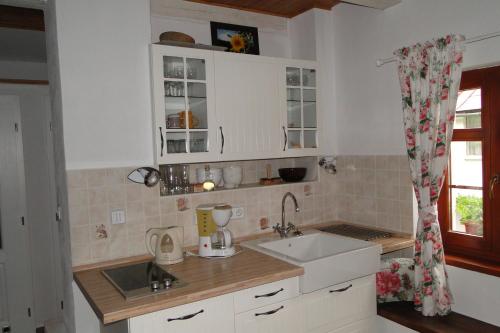 una cucina con armadi bianchi, lavandino e finestra di Rozpravkovy Domcek Zvoncek a Donovaly