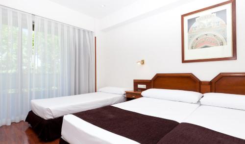 a hotel room with two beds and a window at Senator Barajas in Madrid