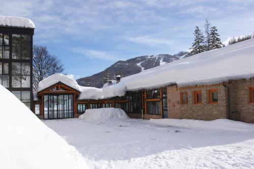 a house covered in snow with a mountain in the background at Hotel Europa in Bardonecchia