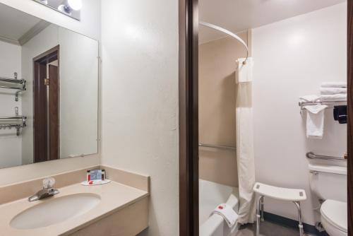 a bathroom with a sink and a toilet and a mirror at Travelodge by Wyndham Livingston in Livingston