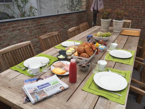 a wooden table with plates and food on it at Hasselt City Garden Duplex in Hasselt