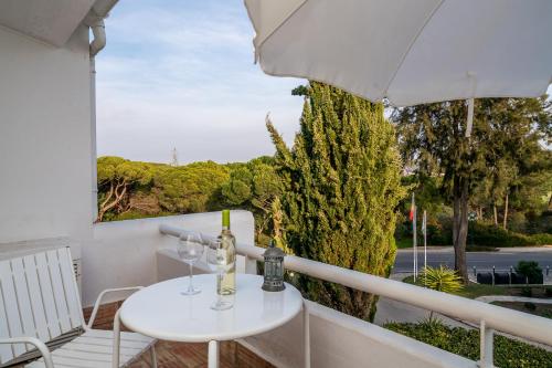 a balcony with a white table and a tree at BmyGuest - Quinta do Lago Lounge Apartment in Almancil
