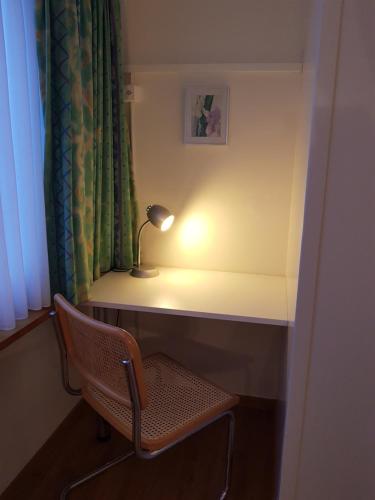 a desk with a lamp and a chair in a room at Hotel Elite in St. Gallen