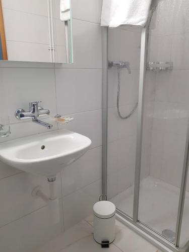 a white bathroom with a sink and a shower at Hotel Elite in St. Gallen