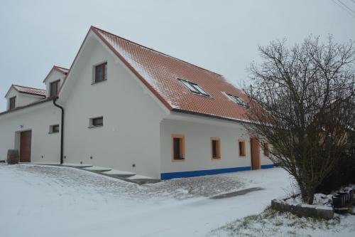 a white building with a red roof in the snow at Vinařství Výmola in Mikulčice