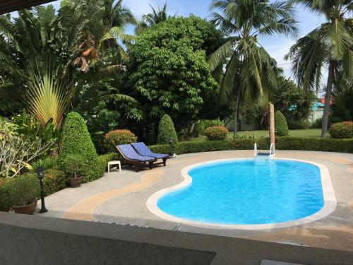 uma piscina num jardim com um banco ao lado em Peaceful homestay em Rawai Beach