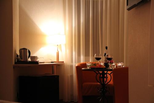 a table with wine glasses and a lamp in a room at Dzintars Hotel in Jūrmala