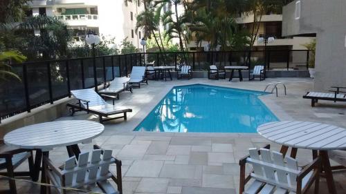 a pool with tables and chairs next to a building at Guarujá Lindo - Pitangueiras in Guarujá