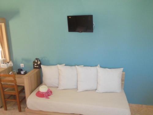 a bed with white pillows and a tv on the wall at Ourania Studios in Sami