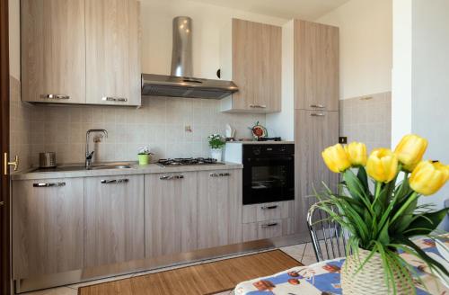 una cocina con armarios de madera y un jarrón con tulipanes amarillos en Casa Mattarella en San Vito lo Capo