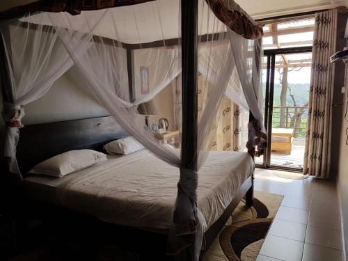 a bedroom with a canopy bed with a window at Living Waters Resort in Jinja