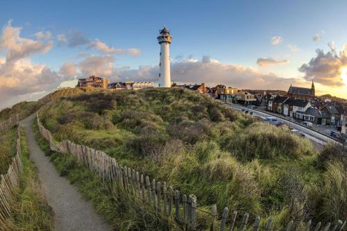 un faro en la cima de una colina con una valla en Apartments Four Seasons Zuiderstraat, en Egmond aan Zee