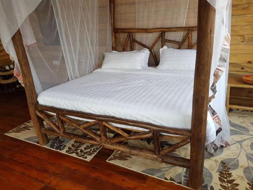 a bed in a room with a wooden frame at Living Waters Resort in Jinja