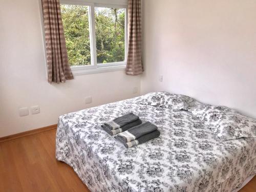 a bedroom with a bed with two towels on it at Apartamento no Centro de Gramado in Gramado