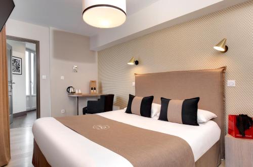 a hotel room with a large bed and a desk at Hôtel des Ducs in Dijon
