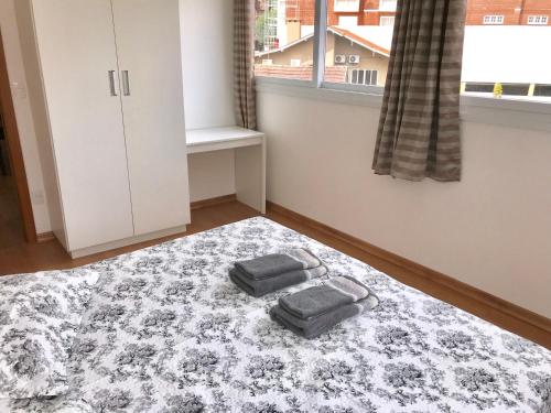 a bedroom with two towels on a bed with a window at Apartamento no Centro de Gramado in Gramado