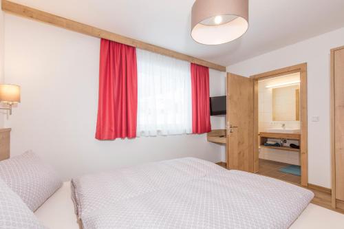 a bedroom with a white bed and a red window at Apart Ida in Sölden