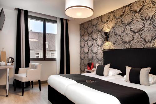 a bedroom with a large bed and a chair at Hôtel des Ducs in Dijon
