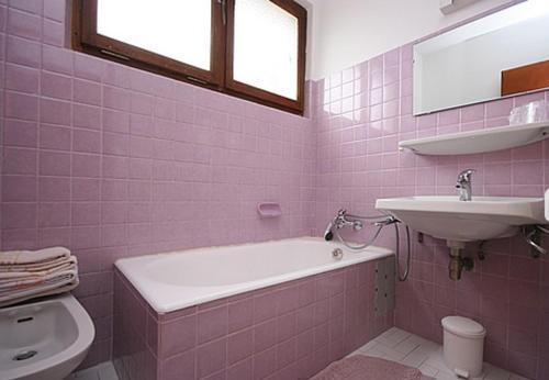 Baño de color rosa con bañera y lavamanos en Le Castellan en Châtel