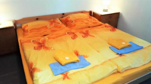 a bed with orange sheets and blue towels on it at Penzion Sumavacek in Bayerisch Eisenstein