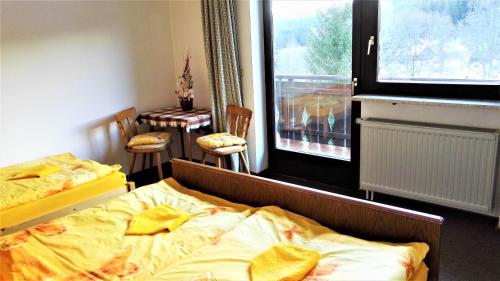 a bedroom with two beds and a table and a window at Penzion Sumavacek in Bayerisch Eisenstein