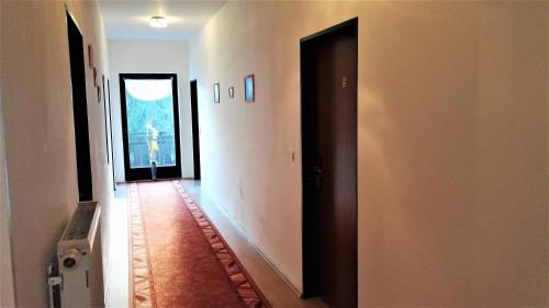 a hallway with a door to a room with paintings at Penzion Sumavacek in Bayerisch Eisenstein