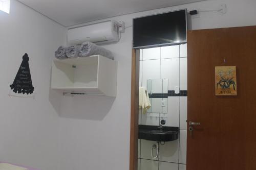 a bathroom with a sink and a mirror and a door at Pousada Orquideas de Maria in Aparecida