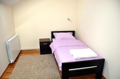 a bedroom with a bed with purple sheets and a rug at Apartments Soleado in Pančevo