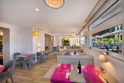 Un restaurante con mesas y sillas y una ventana. en Villa Bettina, en La Baule
