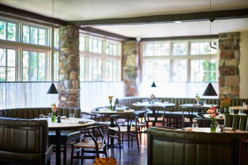 a restaurant with tables and chairs and windows at Troutbeck in Amenia