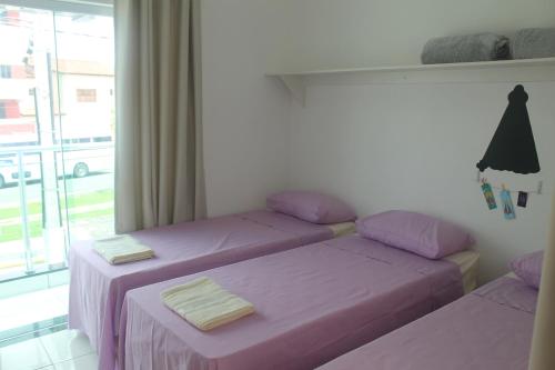 a room with two beds with purple sheets and a window at Pousada Orquideas de Maria in Aparecida