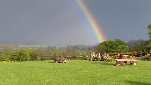a rainbow in a field with a bench and a table at Lus Mor in Roundwood