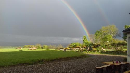 a rainbow in the sky over a green field at Lus Mor in Roundwood