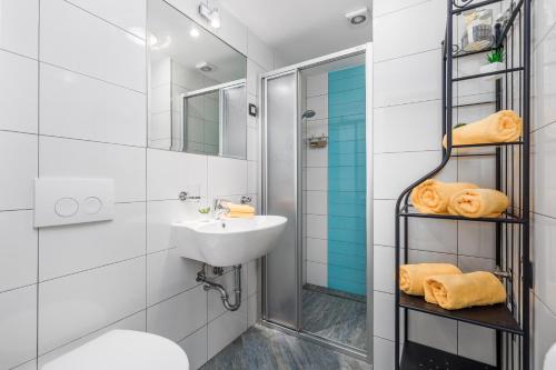 a white bathroom with a sink and a shower at Apartments Linda in Mošćenička Draga