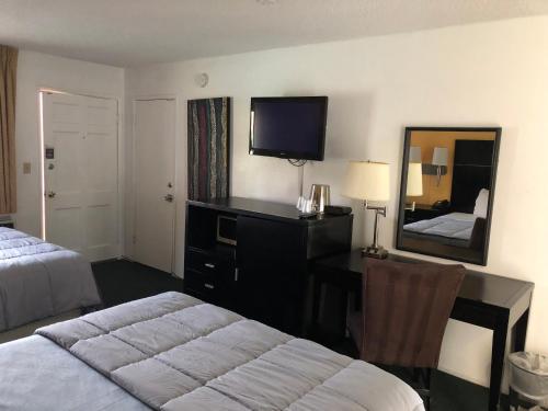 Habitación de hotel con cama, escritorio y espejo. en Desert Lodge, en Palm Springs