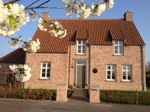 a brick house with a red roof at B&B Het Postenhofje in Puiflijk