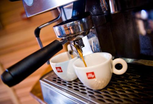a coffee machine pouring coffee into two cups at Bianca's House Hotel Heathrow Airport in Hillingdon
