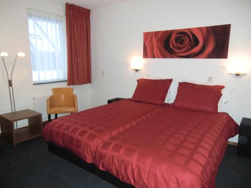 um quarto de hotel com uma cama vermelha e uma rosa vermelha na parede em Horsetellerie Rheezerveen em Hardenberg