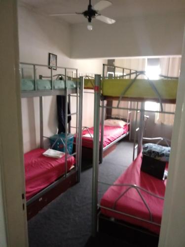 a room with three bunk beds with red sheets at Residencia Hostel in Vila Anastácio