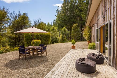 a patio with a table and chairs and an umbrella at Beech Hill - Pet Friendly Holiday Home in Tasman