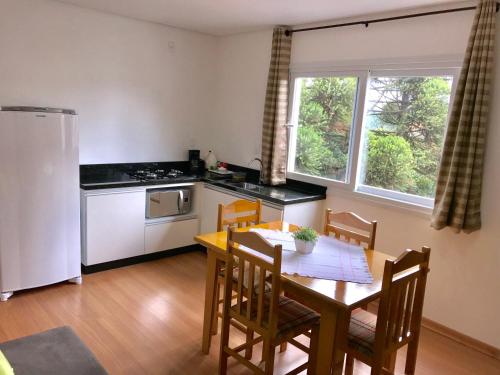 a kitchen with a table and a kitchen with a refrigerator at Apartamento no Centro de Gramado in Gramado