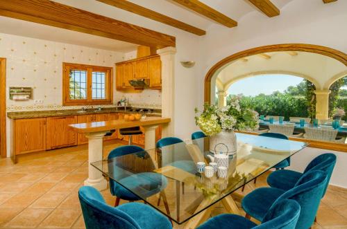 Balcon del MarにあるVilla Miramar, Luxury Villa Rental - Javeaのオープンキッチン、ダイニングルーム(ガラステーブル、青い椅子付)