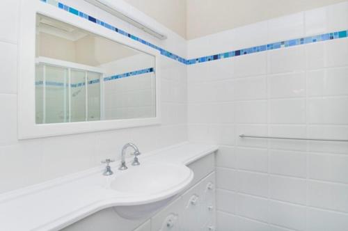 un bagno bianco con lavandino e specchio di Bay Park Gardens 30 1 Warlters Street a Port Macquarie