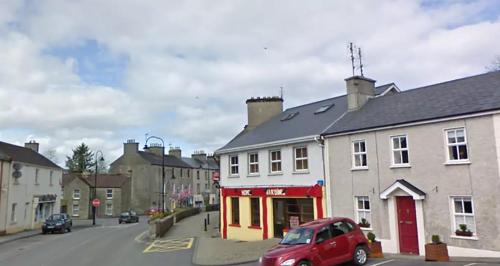 a red car parked in front of a building on a street at Archie's Rest in Drumshanbo