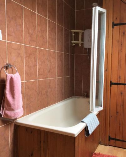 a bath tub in a bathroom with a pink towel at Meadow Sweet Cottage in Okehampton