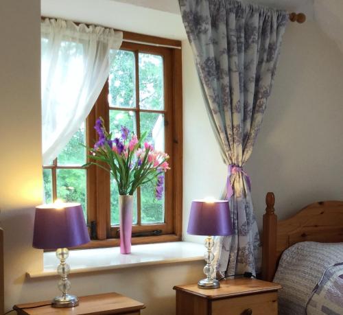 sypialnia z oknem i wazą kwiatów w obiekcie Meadow Sweet Cottage w mieście Okehampton