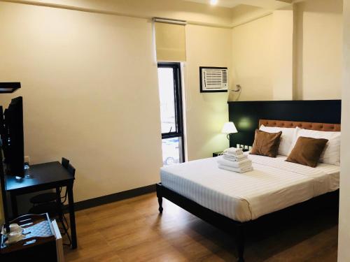 a bedroom with a bed and a desk and a window at Achievers Airport Hotel in Manila