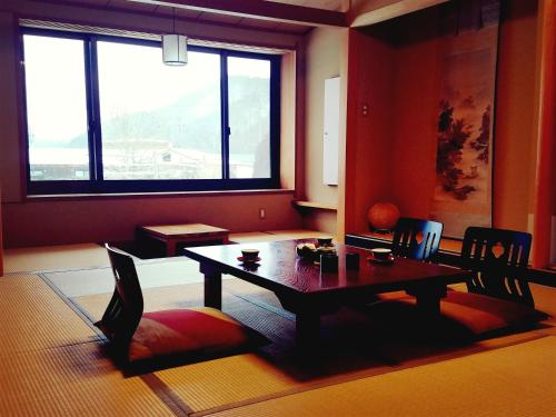 a dining room with a table and chairs and a window at Ryokan Yamakanoyu in Kiso